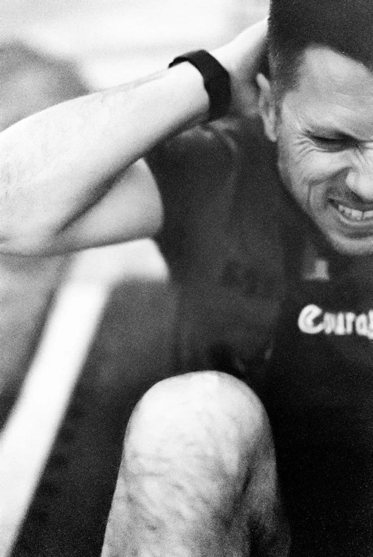 A black-and-white frame of an athlete straining under a loaded barbell