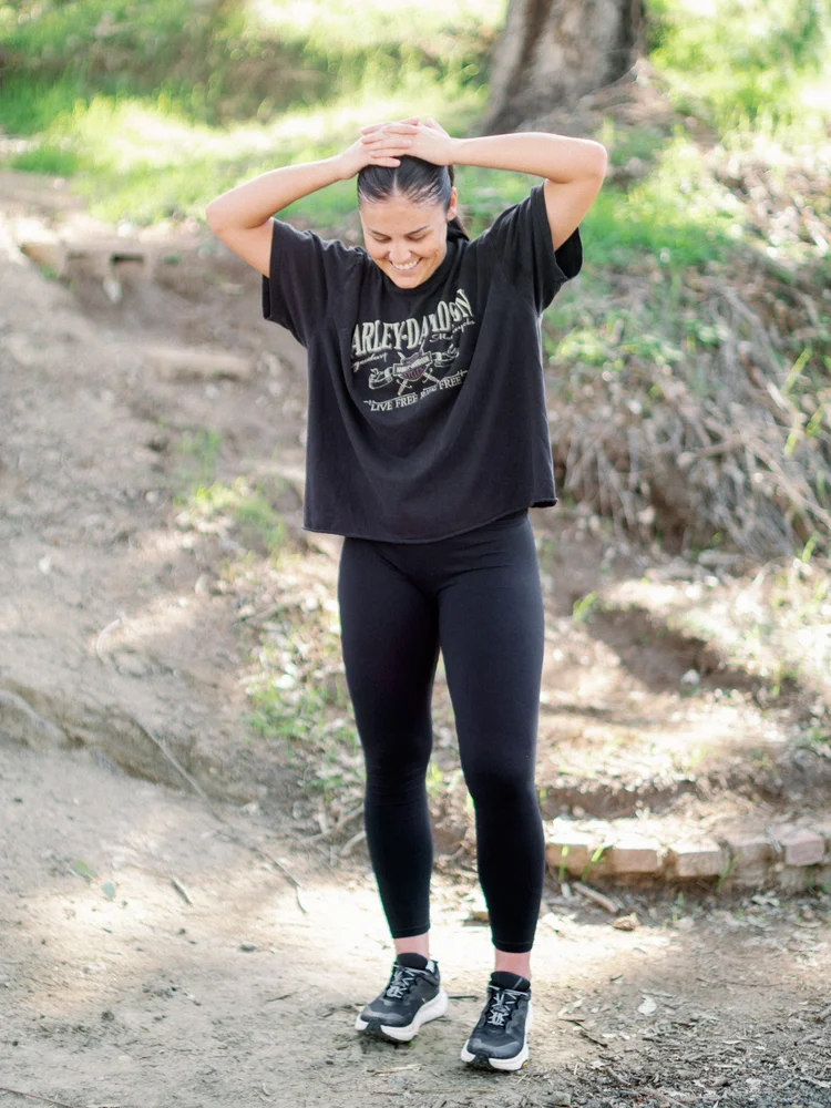 An athlete catching her breath on a trail, hands behind her head